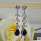 Silver earrings with blue natural zircon gemstones on a rose background
