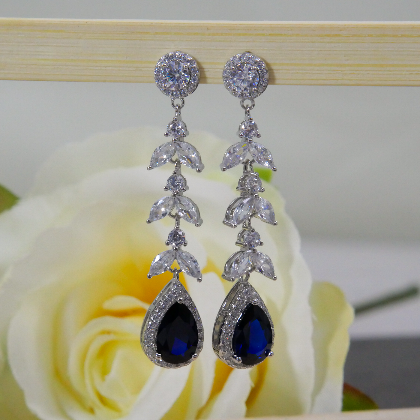 Silver earrings with blue natural zircon gemstones on a rose background
