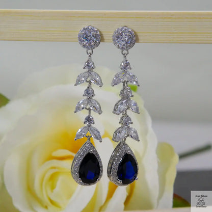Silver earrings with blue natural zircon gemstones on a rose background