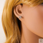 Close-up of an ear wearing a silver earring with a white background