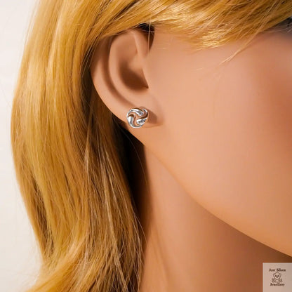 Close-up of an ear wearing a silver earring with a white background