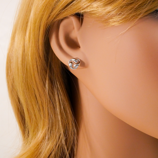 Close-up of an ear wearing a silver earring with a white background