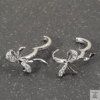 Silver bow-shaped earrings with clear stones on a gray surface