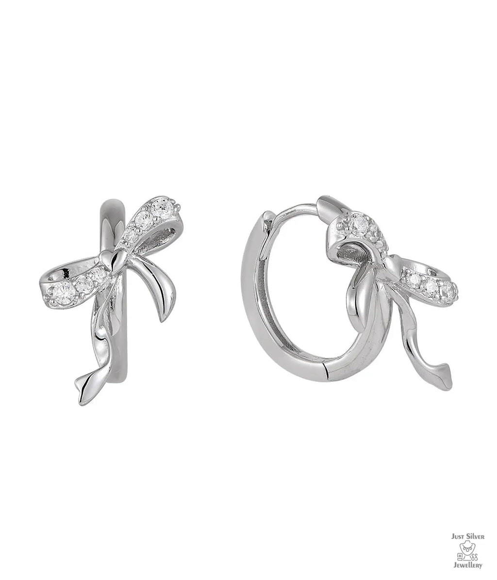 Silver bow-shaped earrings with clear zircon gemstones on a white background