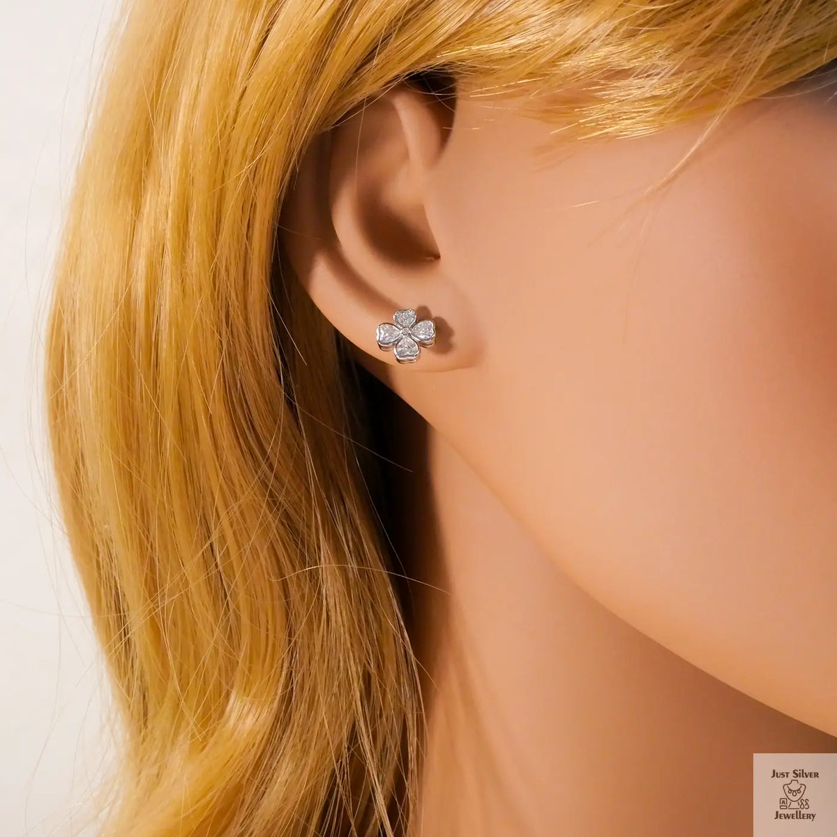 Close-up of a person wearing a silver flower-shaped earring with blonde hair.