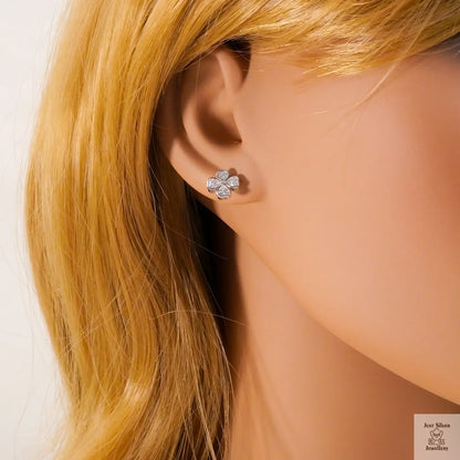 Close-up of a person wearing a silver flower-shaped earring with blonde hair.