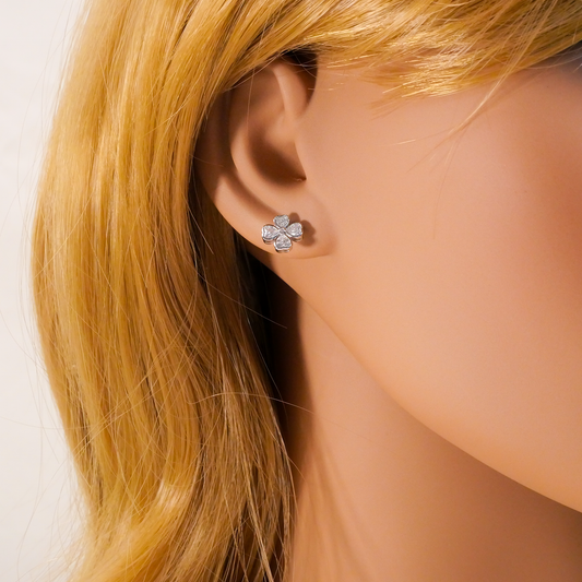 Close-up of a person wearing a silver flower-shaped earring with blonde hair.