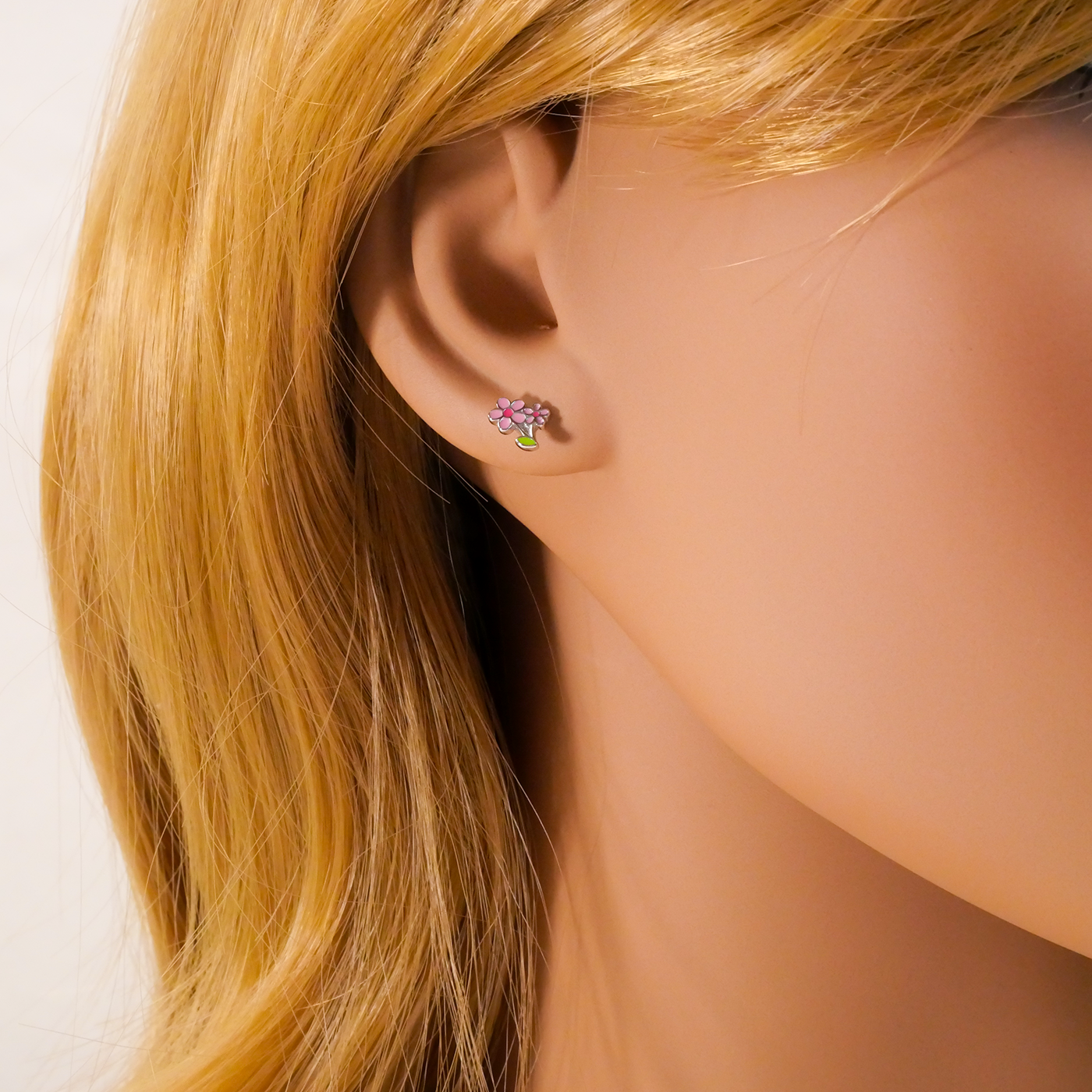 Close-up of a woman wearing a floral stud earring with blonde hair.