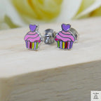 Cupcake-shaped earrings with colorful stripes on a wooden surface