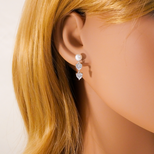Pearl and heart-shaped Natural Zircon gemstone earrings on a mannequin with blonde hair.