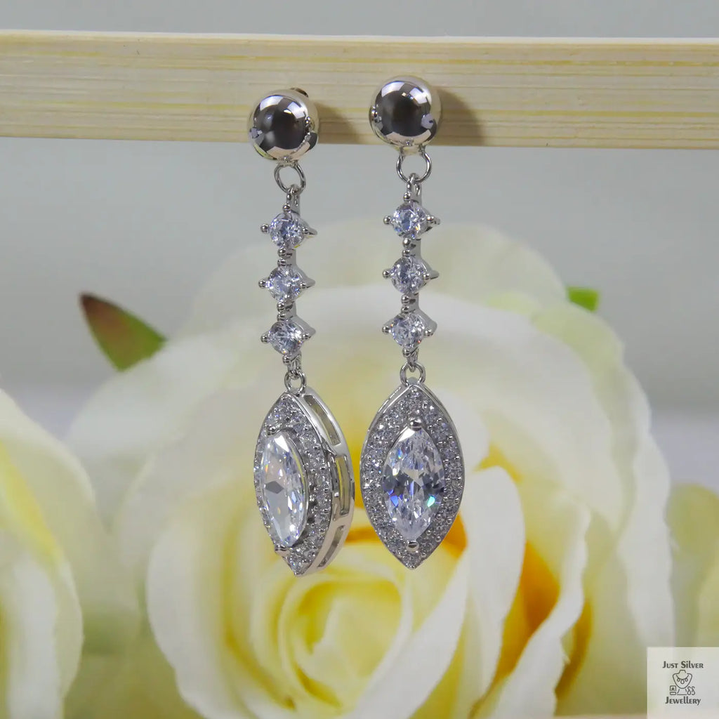 Silver earrings with natural zircon clear stones on a rose in the background