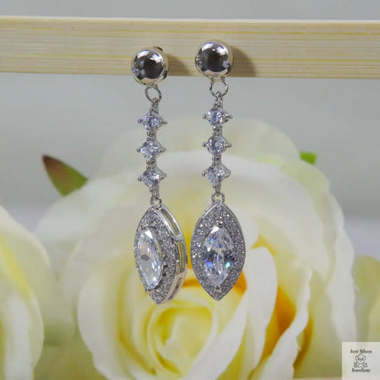 Silver earrings with natural zircon clear stones on a rose in the background