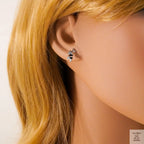 Close-up of an ear wearing a small earring with blonde hair.