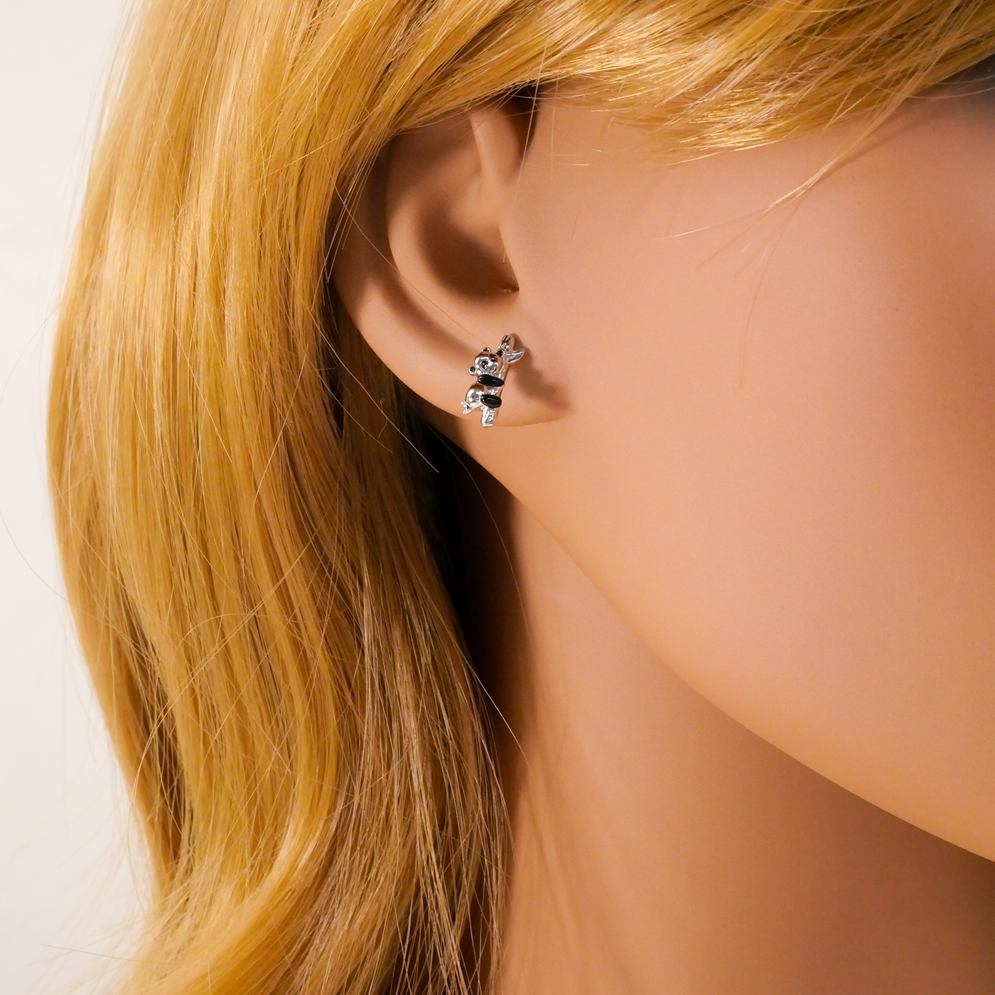 Close-up of an ear wearing a small earring with blonde hair.