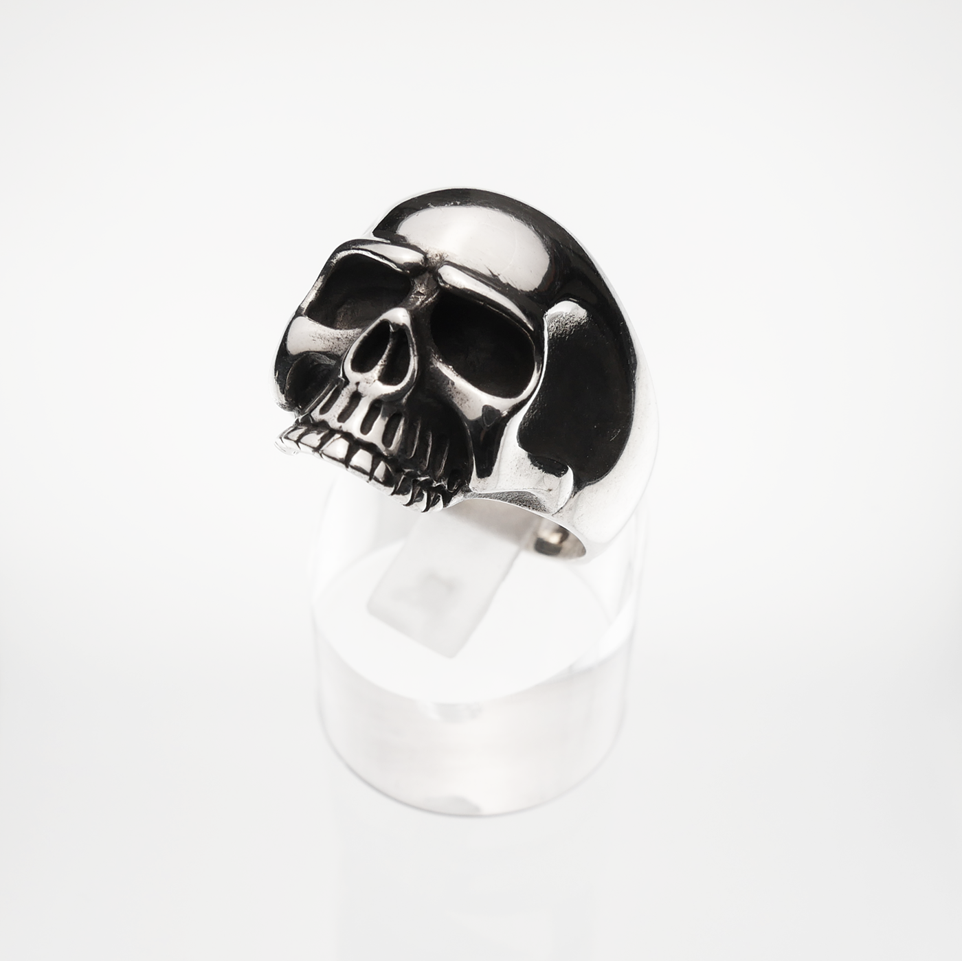 Skull-shaped ring on a clear stand with a white background