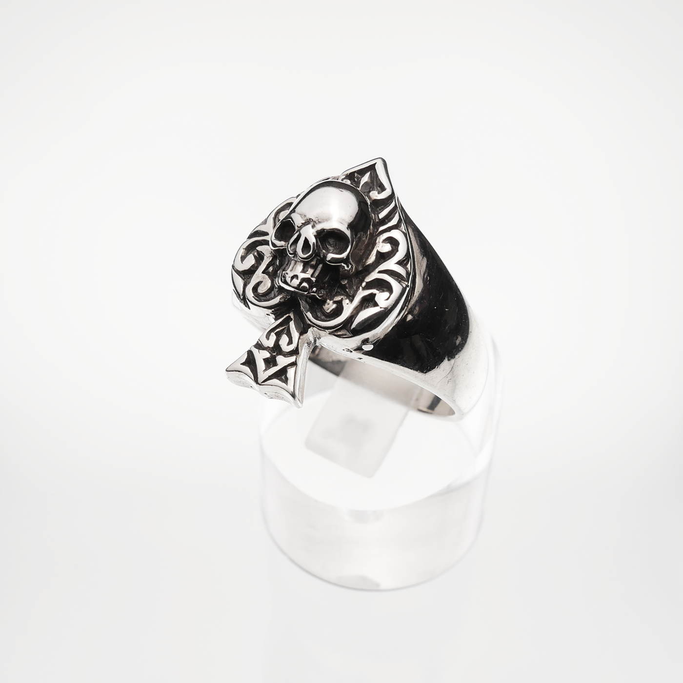 Silver skull ring with intricate designs on a white background