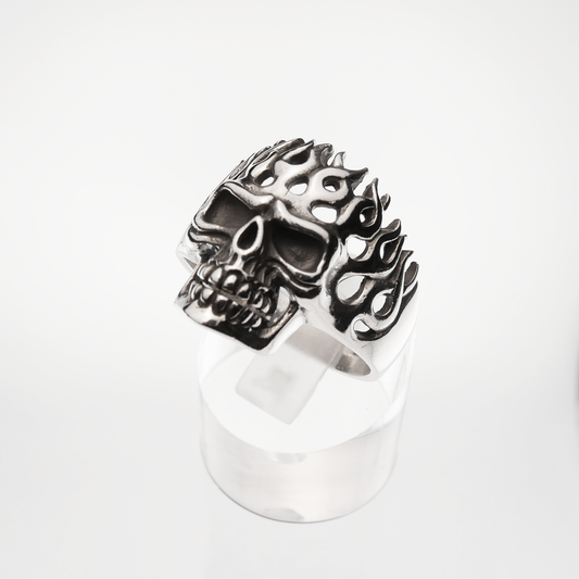 Silver skull ring with flame designs on a white background