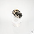 Silver and gold coloured skull ring on a white background