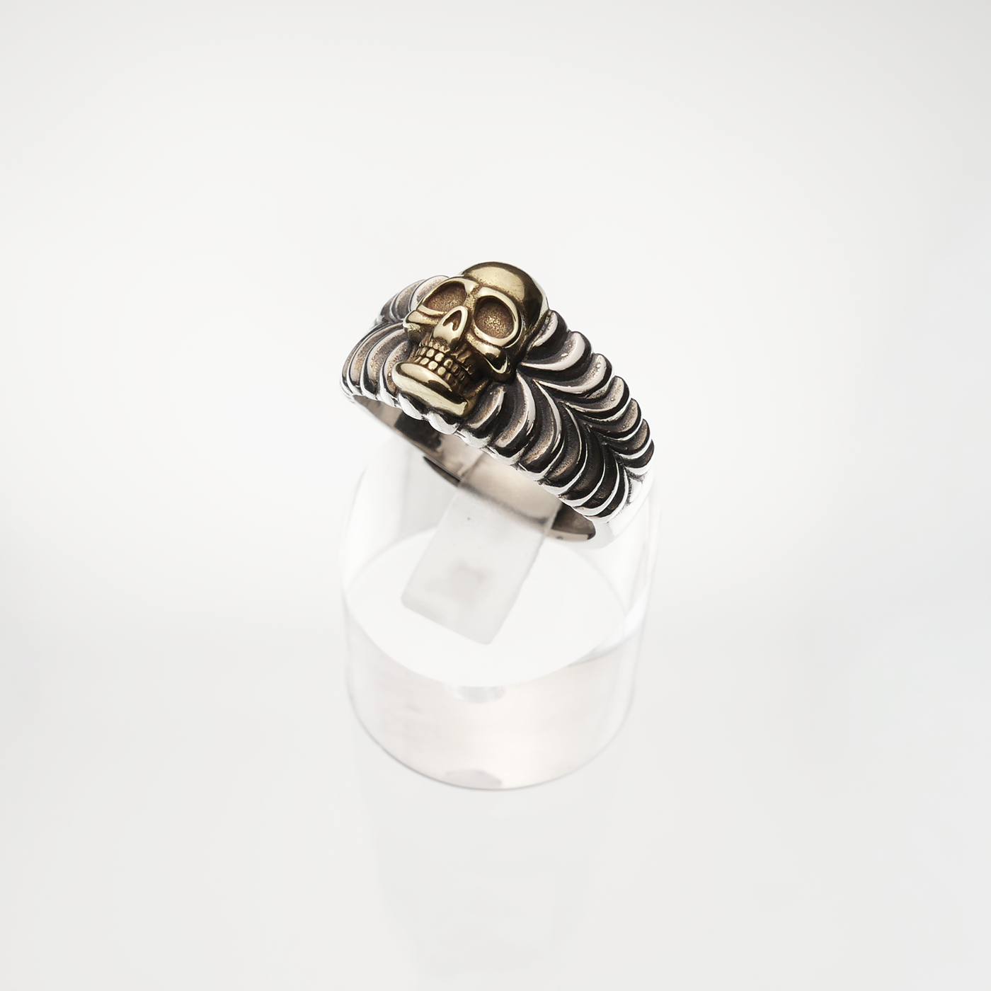 Silver and gold coloured skull ring on a white background