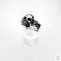 Silver skull ring on a clear stand with a white background