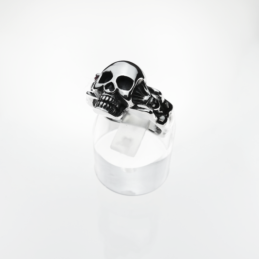 Silver skull ring on a clear stand with a white background