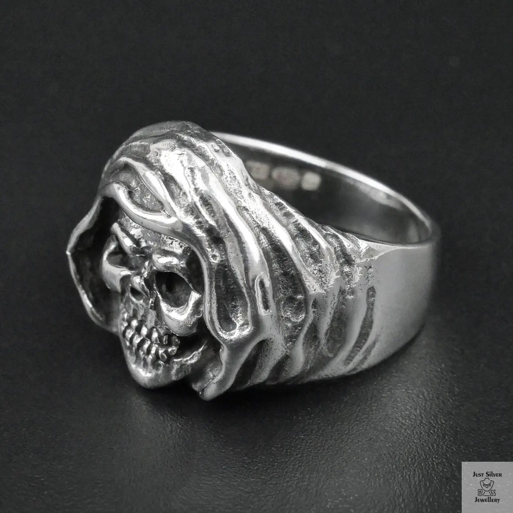 Silver ring with a skull design on a black background