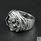 Silver ring with a skull design on a black background