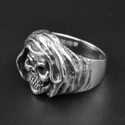 Silver ring with a skull design on a black background