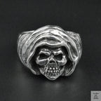Silver ring with skull design on a black background
