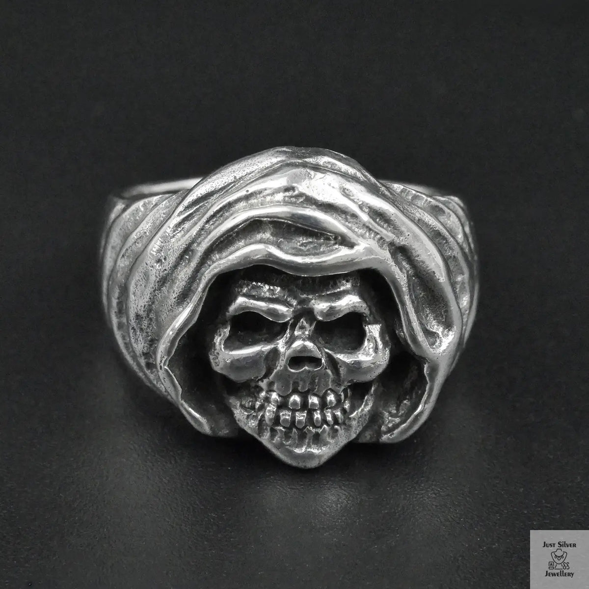 Silver ring with skull design on a black background