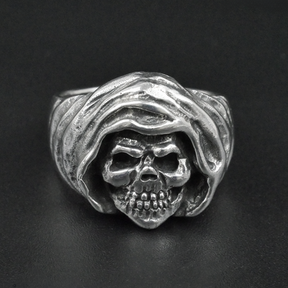 Silver ring with skull design on a black background