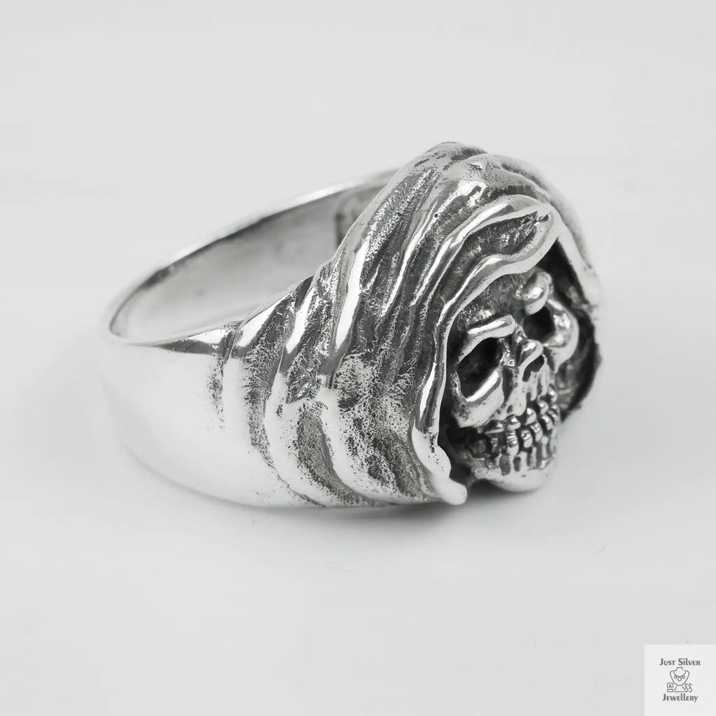 Silver ring with skull design on a light grey background