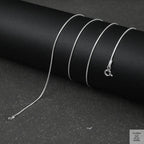 Silver fine snake necklace on a black background