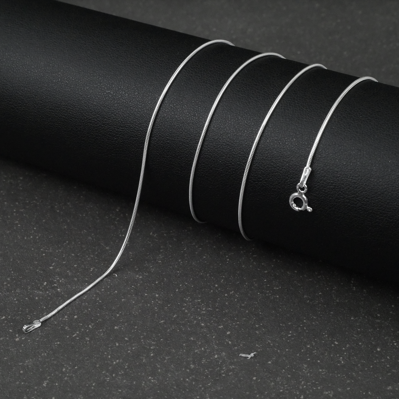 Silver fine snake necklace on a black background