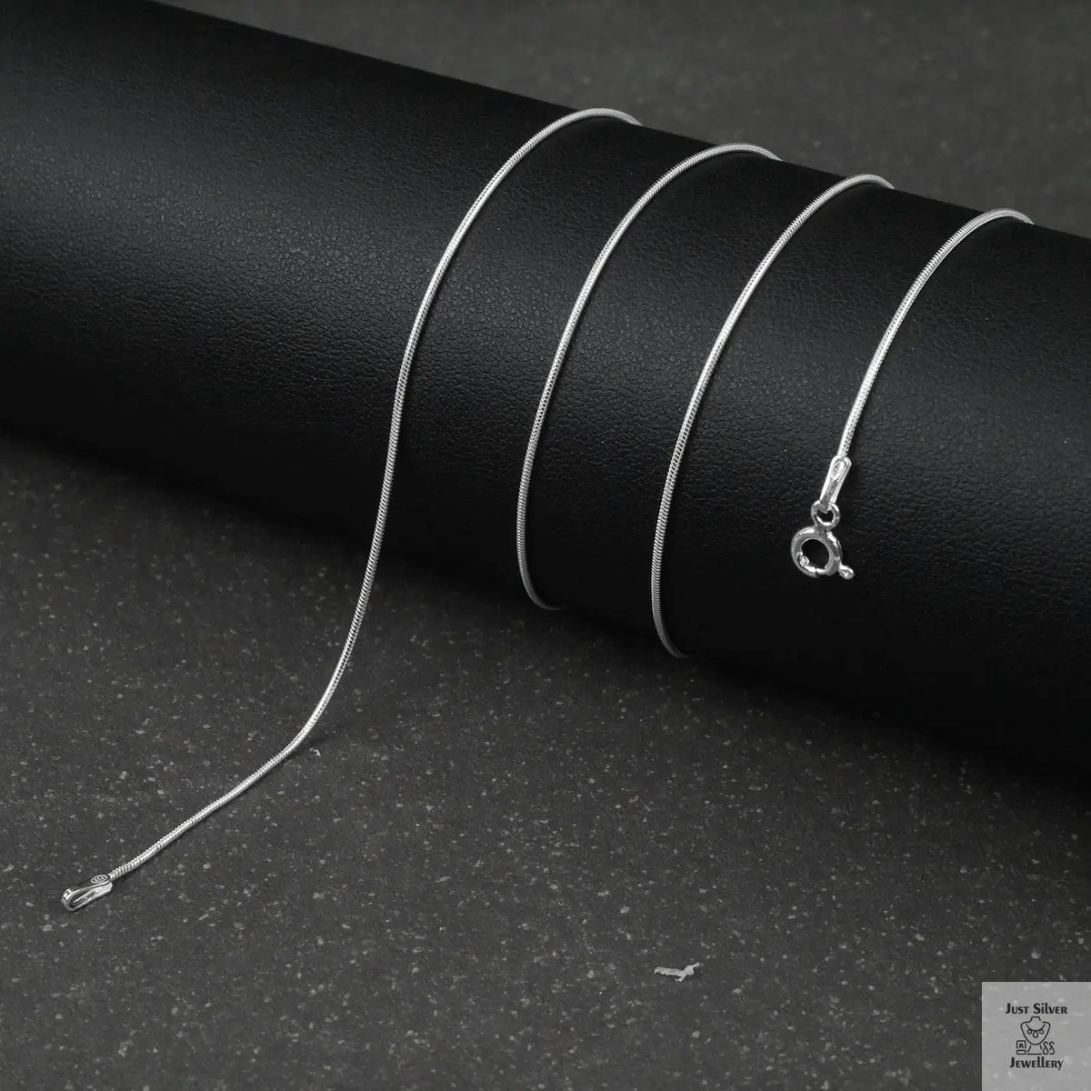 Silver fine snake necklace on a black background