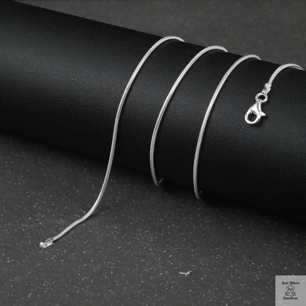 Silver fine snake necklace on a black cylindrical object