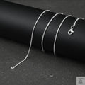 Silver fine snake necklace on a black cylindrical object