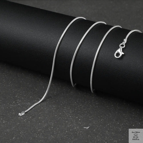 Silver fine snake necklace on a black cylindrical object