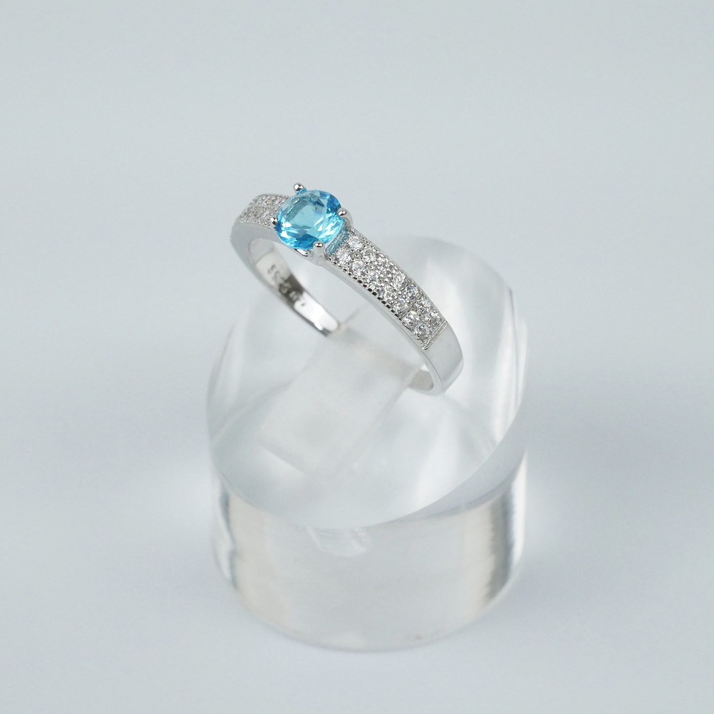 Silver ring with a blue gemstone on a light gray background