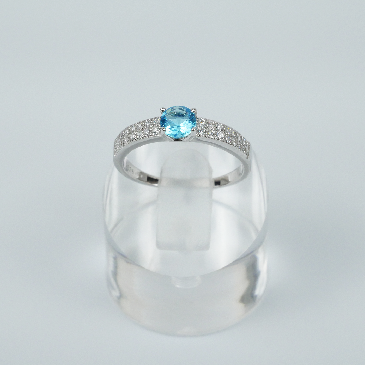 Silver ring with a blue gemstone on a light gray background