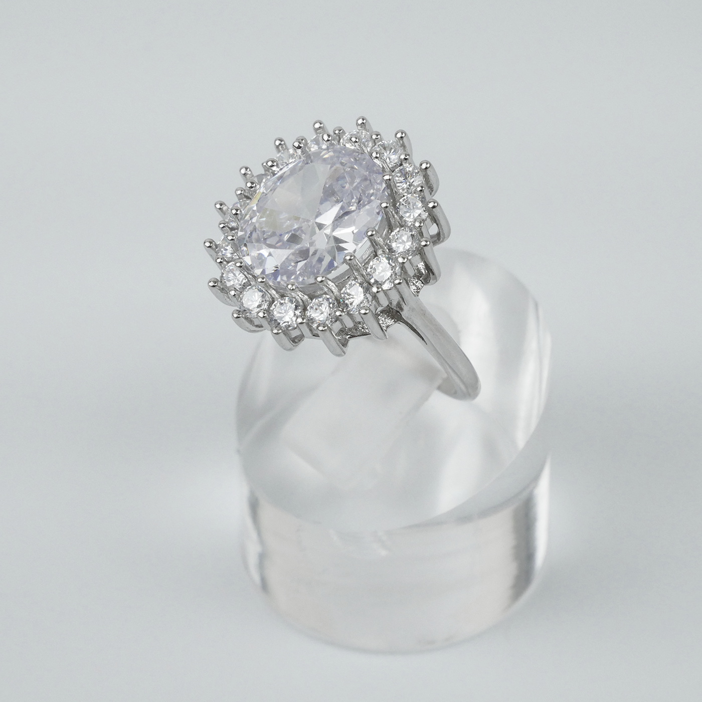 Silver ring with a large central gemstone and smaller stones on a gray background