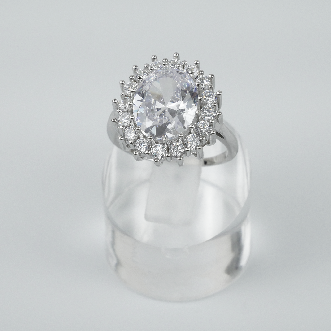 Silver ring with a large central gemstone and smaller stones on a gray background