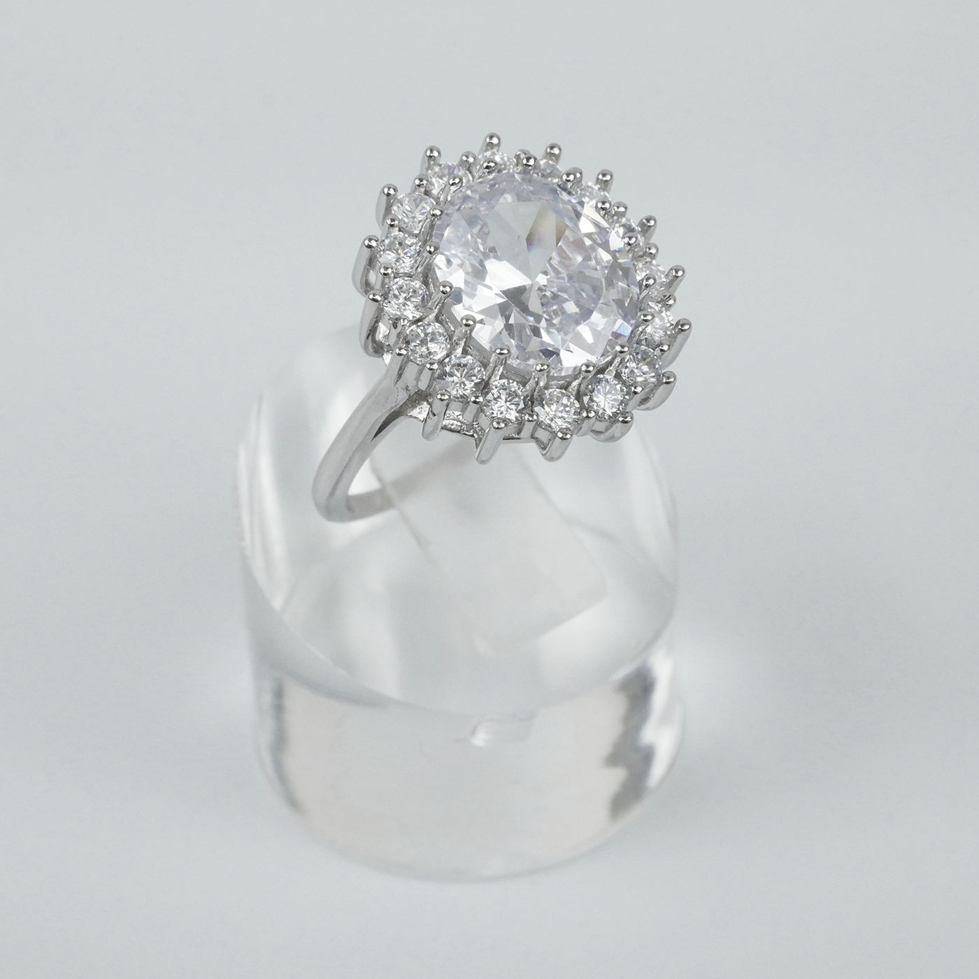 Silver ring with a large central gemstone and smaller stones on a gray background