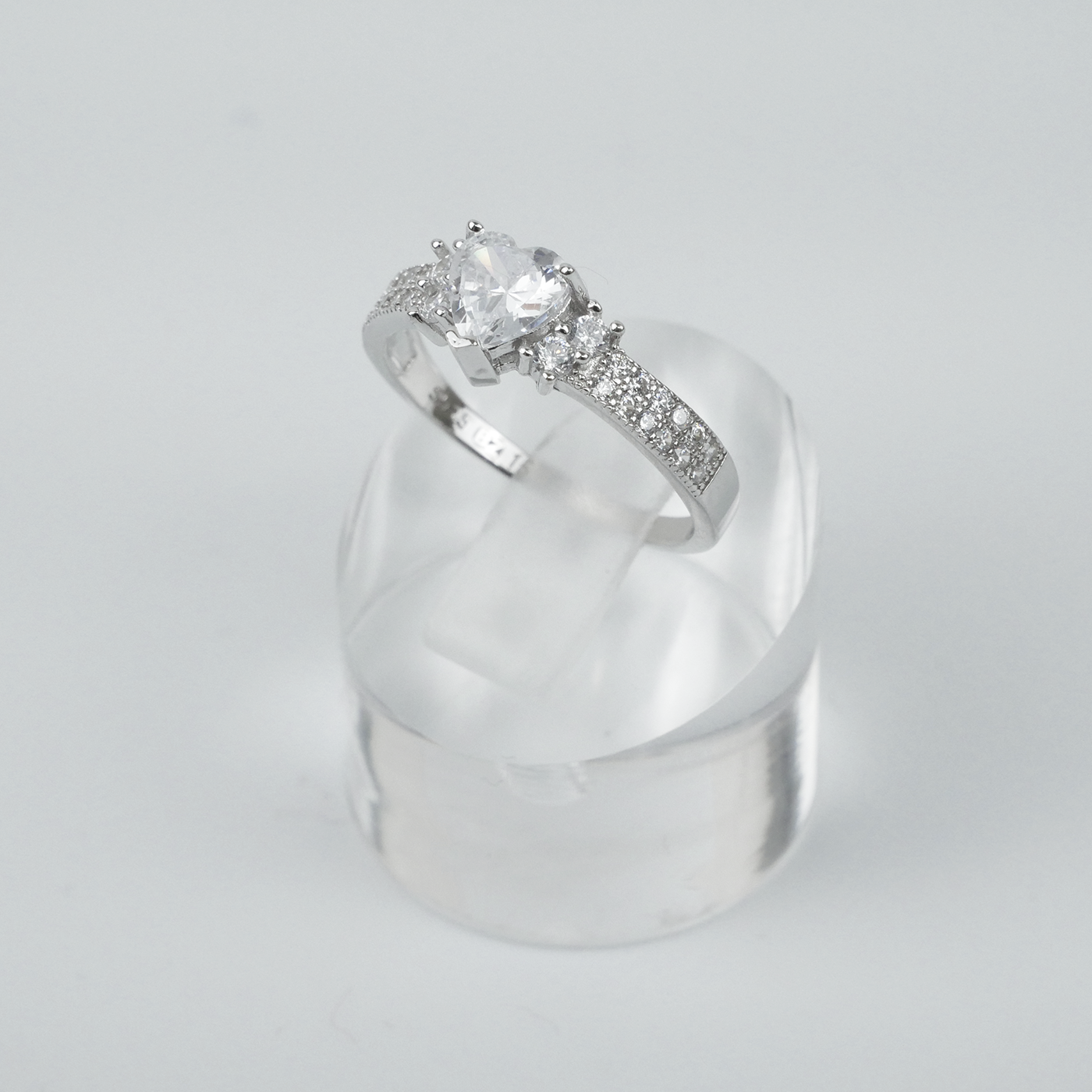 Silver ring with a large central gemstone and smaller stones on a light gray background