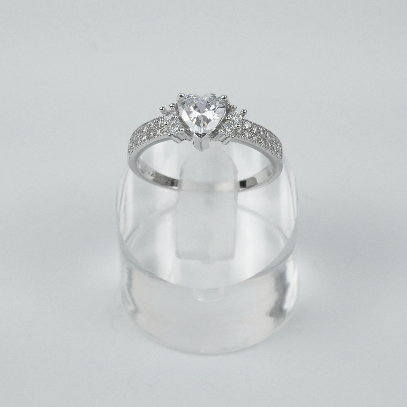 Silver ring with a large central gemstone and smaller stones on a light gray background