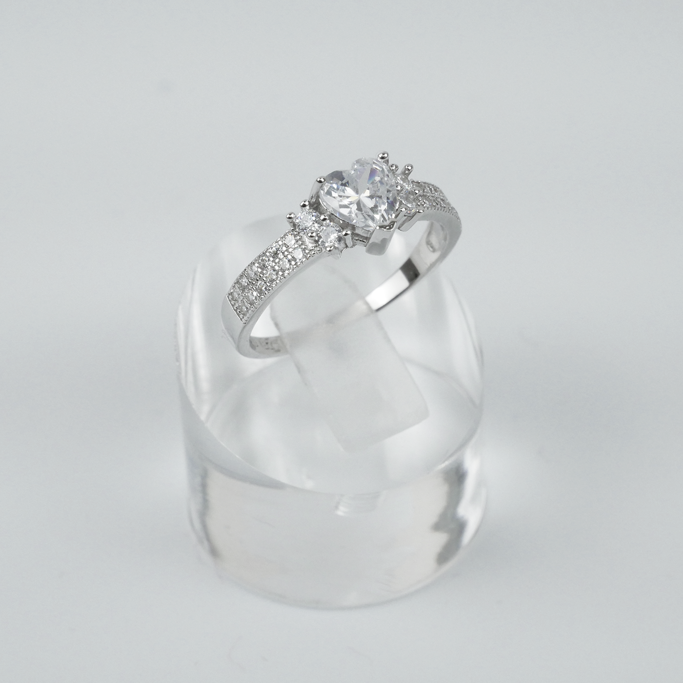 Silver ring with a large central gemstone and smaller stones on a light gray background