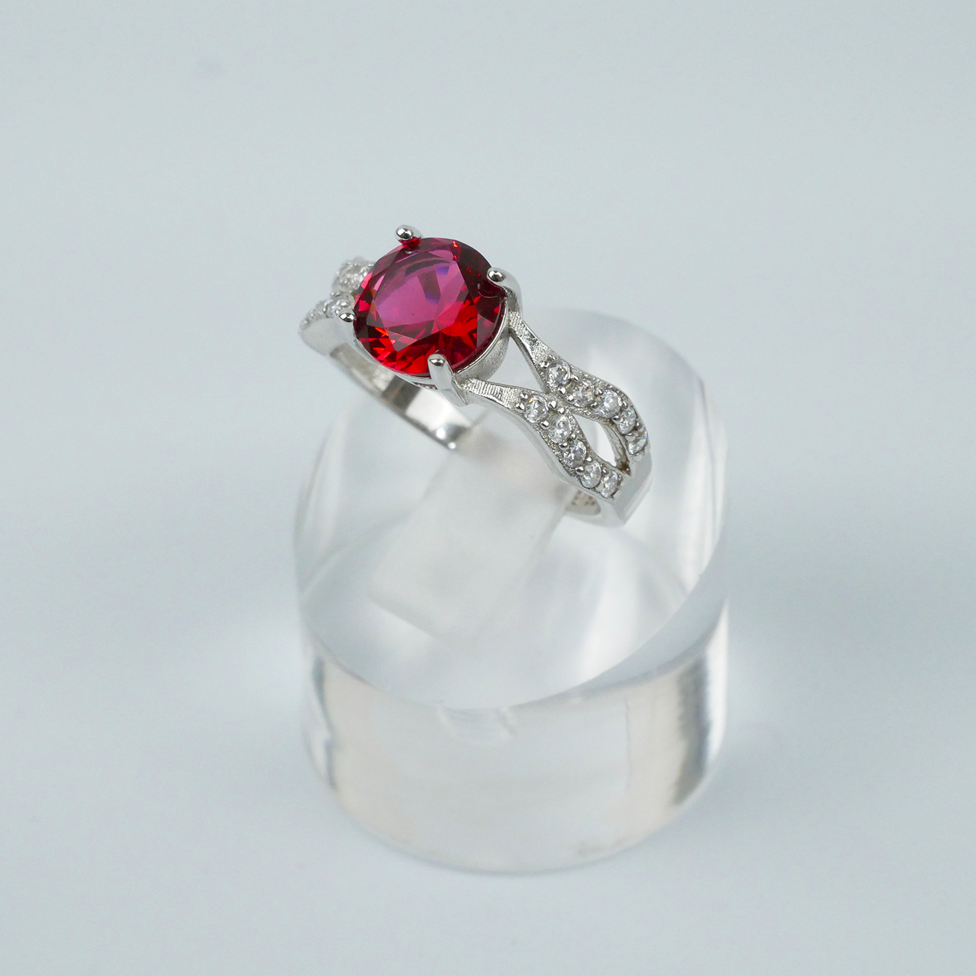 Silver ring with a red gemstone on a light gray background