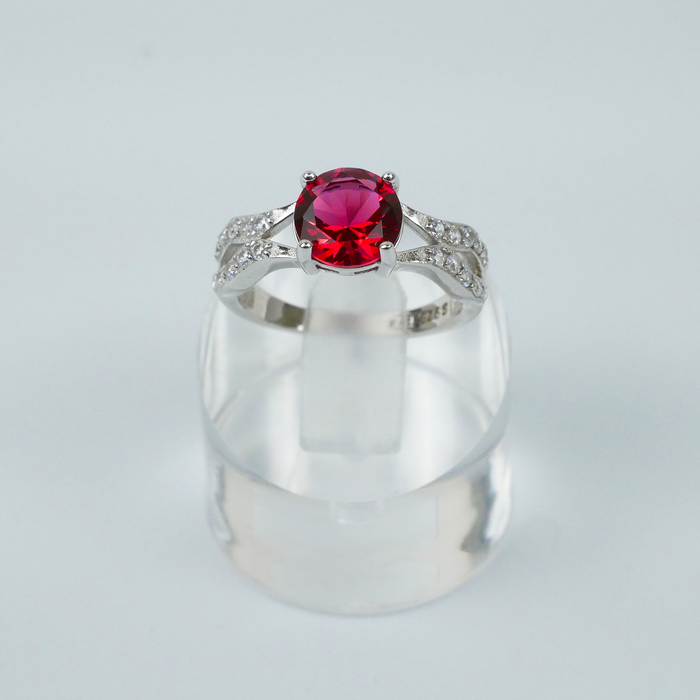 Silver ring with a red gemstone on a light gray background