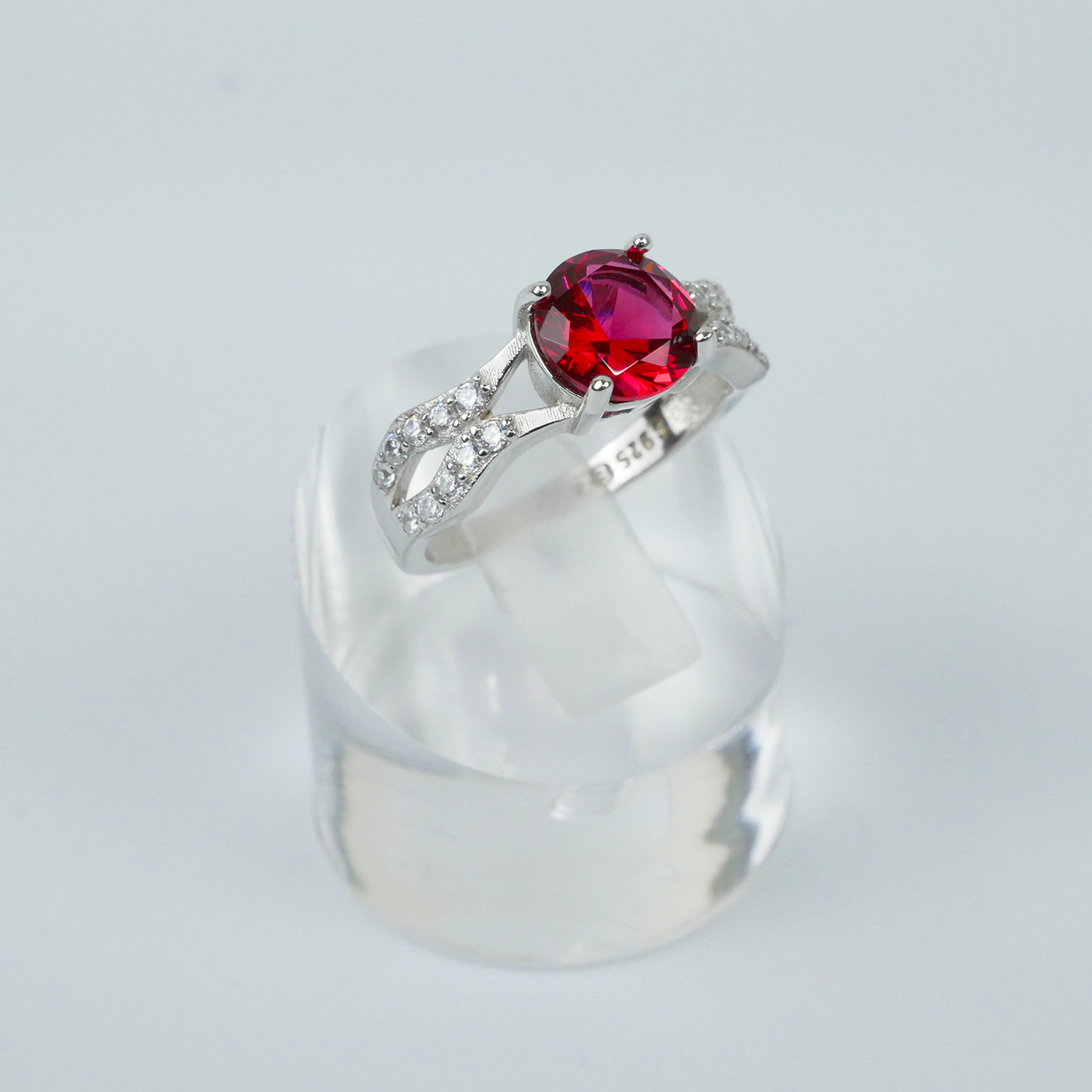 Silver ring with a red gemstone on a light gray background