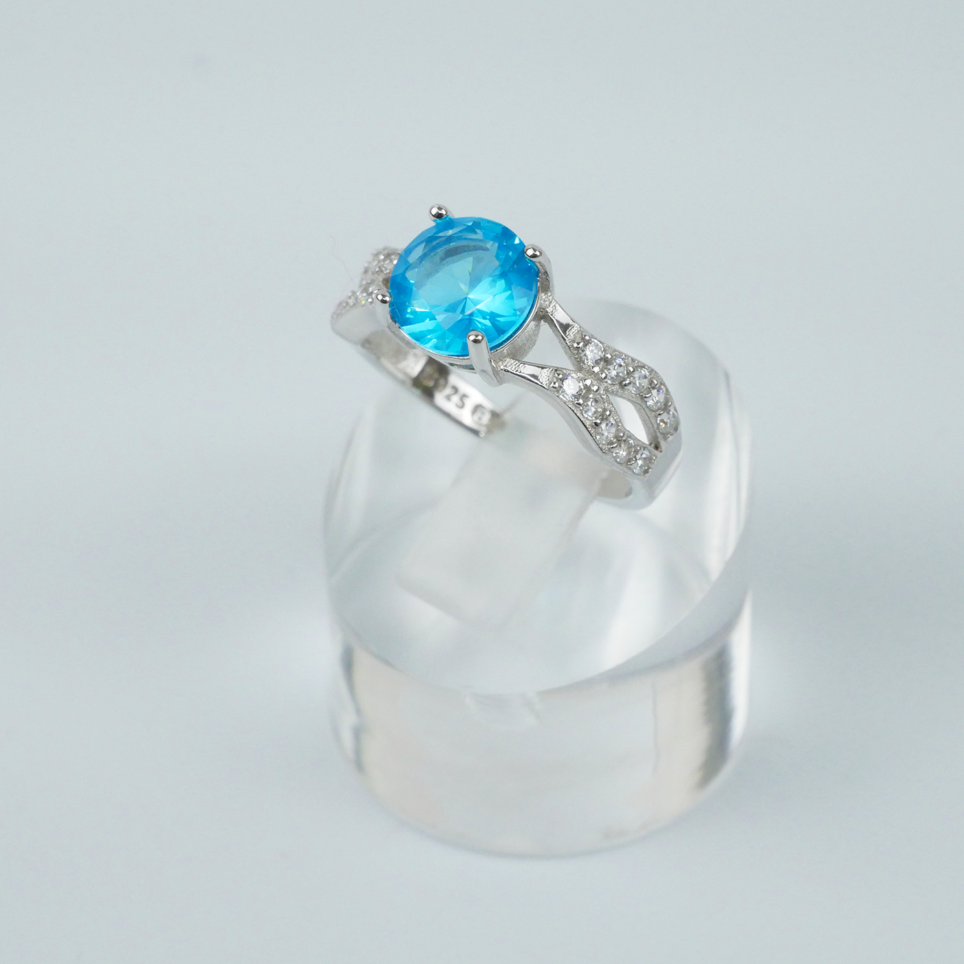 Silver ring with a blue gemstone on a light gray background